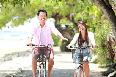 happy asian young couple riding bicycle laughing together
