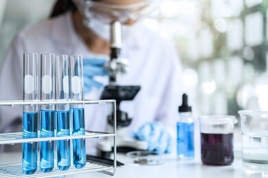 biochemistry laboratory research, chemist is analyzing sample in laboratory with microscope equipment and science experiments glassware containing chemical liquid.