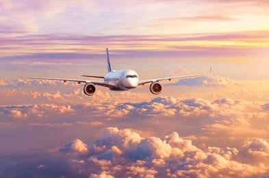 airplane airliner flies over beautiful evening clouds, in the sky at sunset