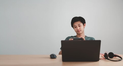 portrait of a man working from home are playing game on mobile and using laptop with copy space background ,business concept.