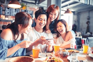happy young people sitting in  restaurant and taking  photo for foods