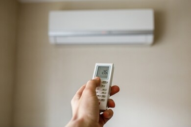 turning on the air conditioner with the remote control in the hand