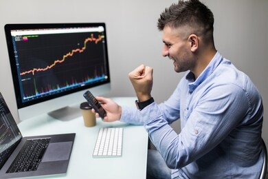businessmen trading stocks online. stock brokers looking at graphs, indexes and numbers on multiple computer screens. colleagues in discussion in traders office. business success concept.