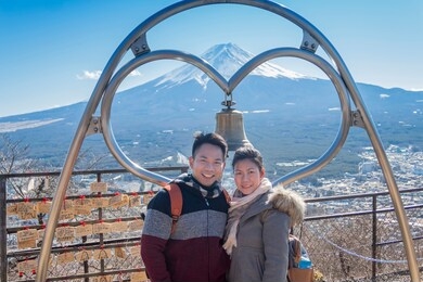 a couple takes a photo with mountain fuji as background with clear blue sky in kawaguchiko city. tokyo, japan february 9, 2020