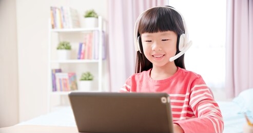 asian girl student wear headset microphone and use tablet pc to have online language class happily at home