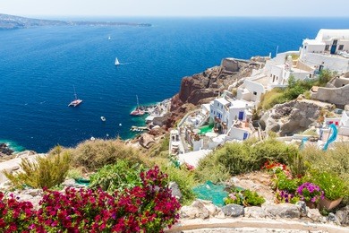 view of fira town - santorini island,crete,greece. white concrete staircases leading down to beautiful bay with clear blue sky and sea