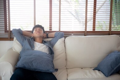 portrait young handsome asian man napping relax with cozy on sofa at home, asia male resting and sleeping in weekend with tired and lazy on couch in vacation, lifestyle and wellbeing concept.