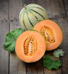 cantaloupe melon with fresh leaves on wooden background.