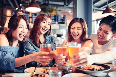 happy young group dining and drinking beer at restaurant