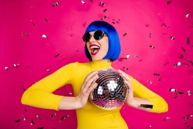 photo of funny excited lady student party nightclub hold disco ball dancing queen confetti fall wear retro specs yellow turtleneck blue short wig isolated bright pink color background