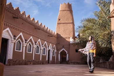 east asian young tourist woman visits a mosque of traditional architecture style, in ushaiqer traditional village, saudi arabia
