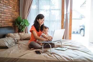 asian young woman working while taking care of her children at home