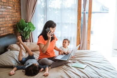asian young woman working while taking care of her children at home