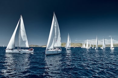 sailboats compete in a sail regatta at sunset, race of sailboats, reflection of sails on water, multicolored spinnakers, number of boat is on aft boats, bright colors