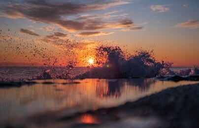 romantic view of sea sunset and waves. spray of water and rocky beach. sunset sun and twilight.