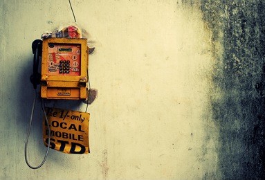 an old looking public phone on a rusty wall