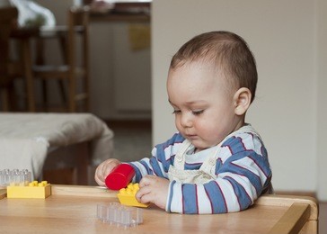 baby or toddler child playing with plastic blocks at home. 
