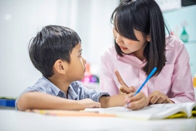 asian female teacher teaching kid writing lesson and reading book in classroom,pecial education during school holidays.