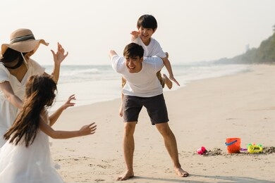 asian young happy family enjoy vacation on beach in the evening. dad, mom and kid relax playing together near sea when sunset while travel holiday. lifestyle travel holiday vacation summer concept.