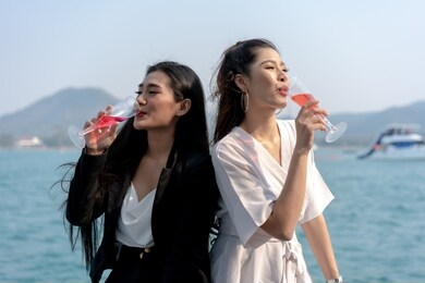 asian women drinking glasses of champagne or wine with her frieds on a yacht. friends happily organized a celebration party and cheers.
