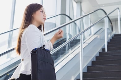 young asian business woman going to work by walking on the stairs and holding her bag. business and finance concept.