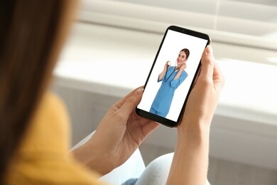 woman using smartphone for online consultation with doctor via video chat, closeup