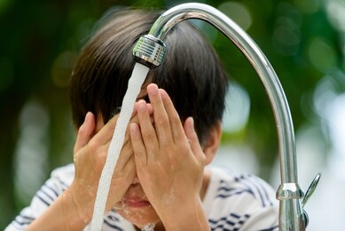 young boy wash his face with water from new faucet at home garden