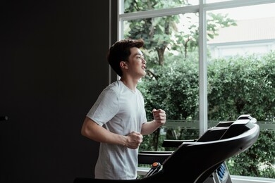 people running in machine treadmill at fitness gym. young man running on a treadmill at home. male athlete workout on running exercise machine.