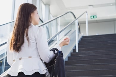 young asian business woman going to work by walking on the stairs and holding her bag. business and finance concept.