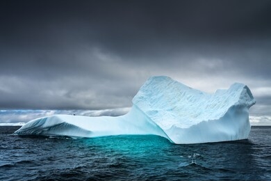 blue iceberg in water under dark clouds  in antarctica