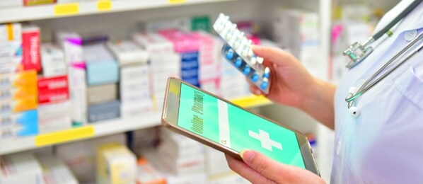 pharmacist holding capsule pack and touch pad for search bar on display in pharmacy drugstore shelves background.online medical concept.