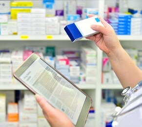 doctor holding medicine box and computer tablet for filling prescription in pharmacy drugstore.