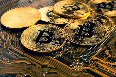 golden coins with bitcoin symbol on a mainboard.