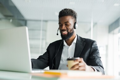 african american customer support operator with hands-free headset working in the office.