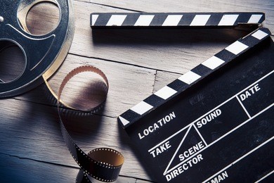 movie clapper and film reel on a wooden background