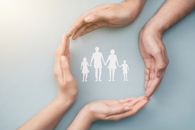 hands with cut out paper silhouette on table. family care concept.