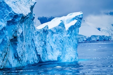 iceberg snow mountains blue glaciers dorian bay antarctic peninsula antarctica.  glacier ice blue because air squeezed out of snow.