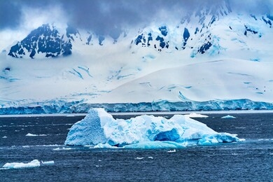 iceberg snow mountains blue glaciers iceberg dorian bay antarctic peninsula antarctica.  glacier ice blue because air squeezed out of snow.