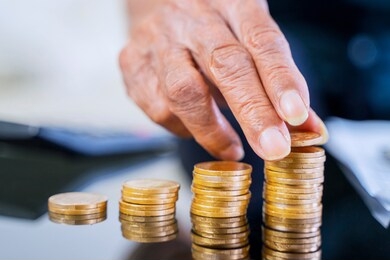 closeup of elderly man hand stacking golden coins on the table