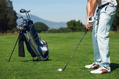 golfer man hitting golf ball from green fairway alone with bag on stand