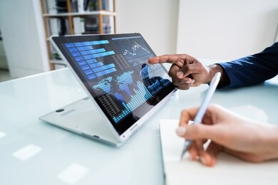 two businesspeople working together with financial graph on laptop