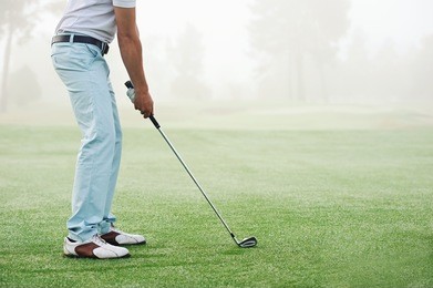 golfer hitting golf shot with club on course while on summer vacation