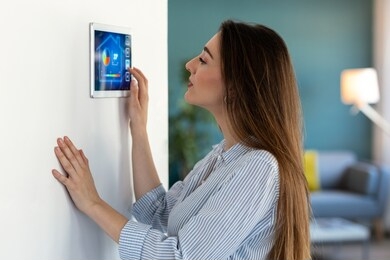 shot of pretty young woman using the home automation system on digital tablet to regulate the temperature.