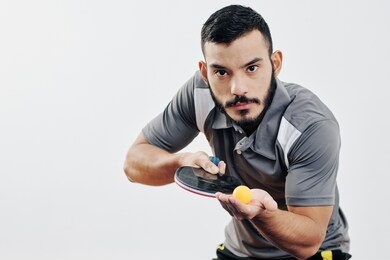 serious young hispanic table tennis player ready to serve ball and start game