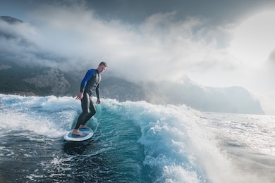 wake surfing. wakeboarder making tricks on sunset. awesome water sport. young man surfer trains at sea.