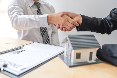 businessmen and brokers real estate agents shake hand after completing negotiations to buy houses insurance and sign contracts. home insurance concept.