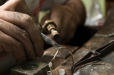 jeweler melting gold bracelet with gasoline burner for making jewelry