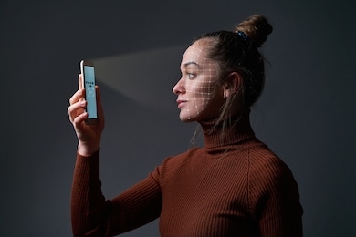 woman scans face using facial recognition system on mobile phone for biometric identification. future high tech technology and face id   
