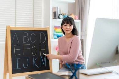 asian woman teacher teaching english alphabet via video conference e-learning to elementary school student, homeschooling and distance learning ,online ,education and internet.
