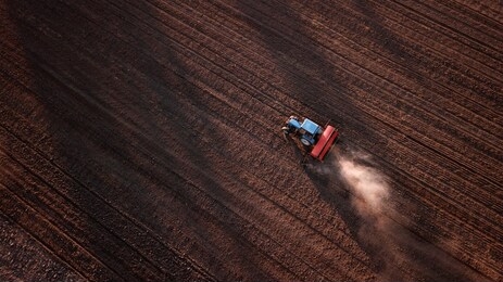 aerial view of tractor , combine cultivating field. drone shot. picture with space for text. farmland from above
